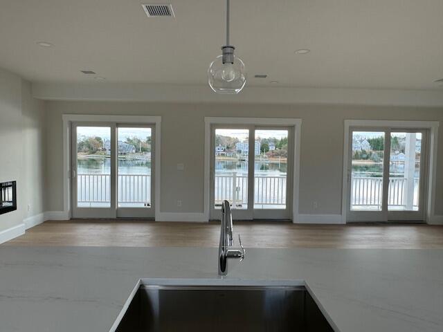 kitchen featuring sink, a water view, and hanging light fixtures