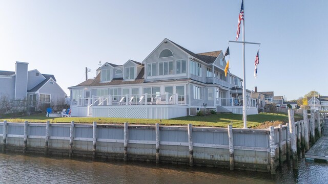 rear view of property with a yard, a water view, fence, and a sunroom