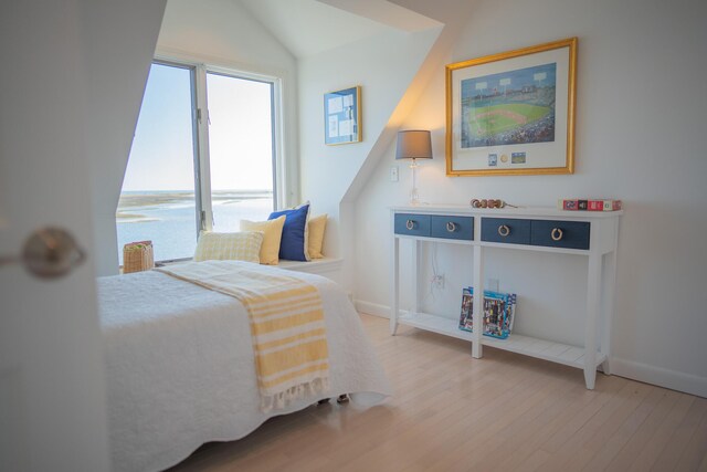 bedroom featuring baseboards, light wood-style flooring, and lofted ceiling