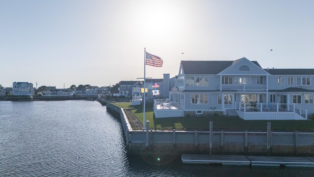 view of dock featuring a lawn, a water view, fence private yard, and a balcony