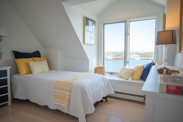 bedroom featuring baseboard heating, lofted ceiling, and wood finished floors