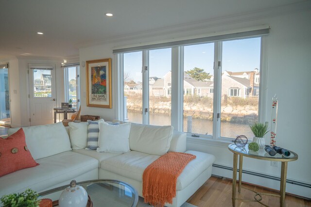 living room with a water view, plenty of natural light, baseboard heating, and wood finished floors