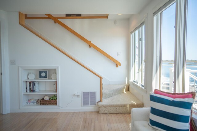 living area with visible vents, a healthy amount of sunlight, stairway, and wood finished floors