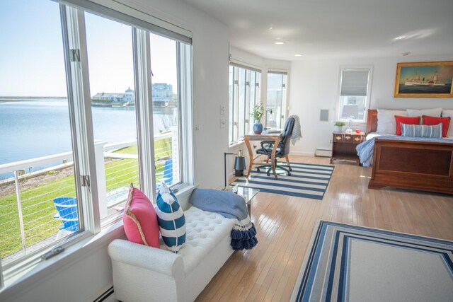 bedroom with wood-type flooring, baseboard heating, recessed lighting, a water view, and a baseboard radiator