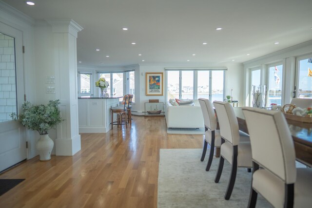 dining space featuring light wood-style floors, ornamental molding, decorative columns, and recessed lighting