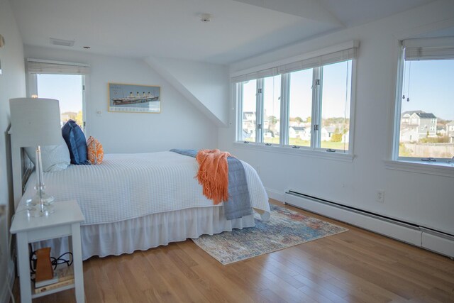 bedroom with visible vents, wood finished floors, baseboard heating, and multiple windows