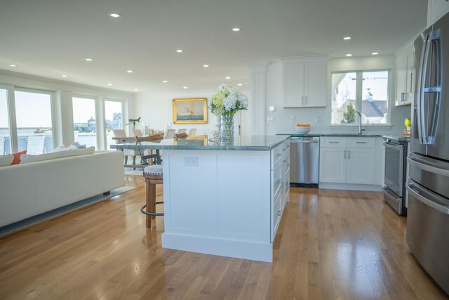 kitchen with stainless steel appliances, open floor plan, white cabinetry, and a wealth of natural light