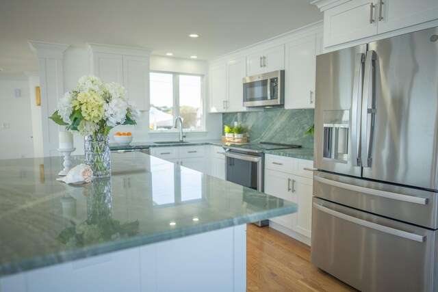 kitchen with decorative backsplash, appliances with stainless steel finishes, a sink, recessed lighting, and white cabinetry