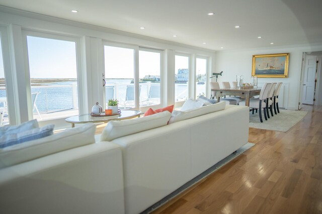 living room with a water view, recessed lighting, ornamental molding, and light wood-style floors