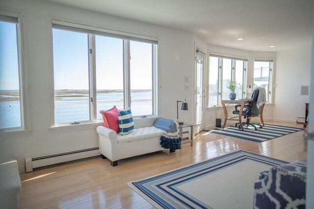 living area featuring wood finished floors, a baseboard radiator, a baseboard heating unit, a water view, and recessed lighting