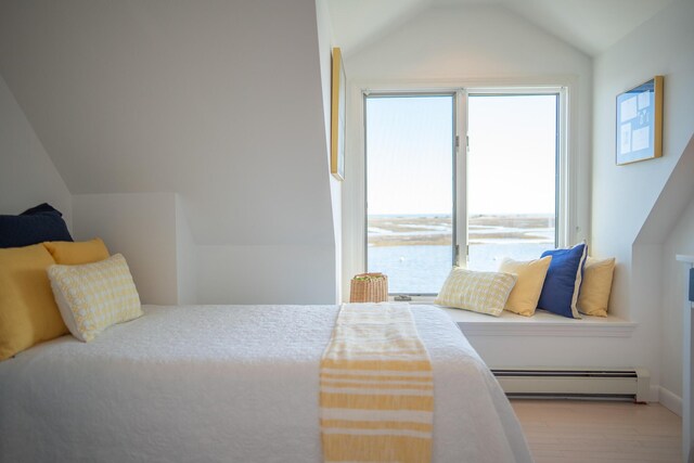 bedroom with a baseboard heating unit, multiple windows, wood finished floors, and vaulted ceiling