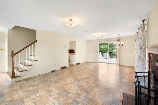 75 Wing Blvd E, East Sandwich, MA 02537 - unfurnished living room with a chandelier, stone finish flooring, stairs, and a brick fireplace