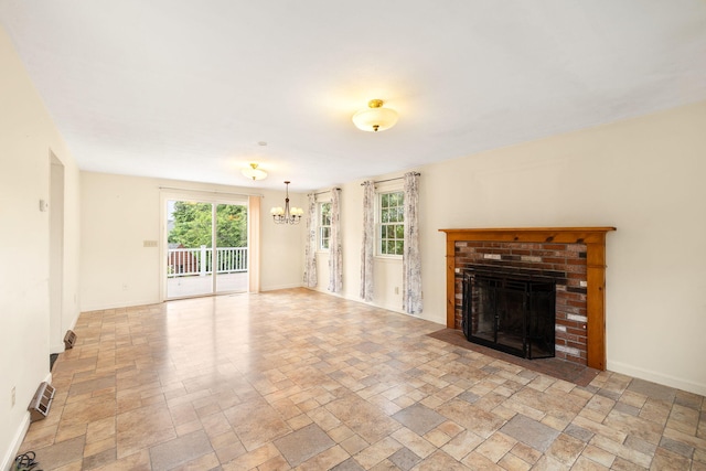 75 Wing Blvd E, East Sandwich, MA 02537 - unfurnished living room with a chandelier, a brick fireplace, and light stone finish flooring