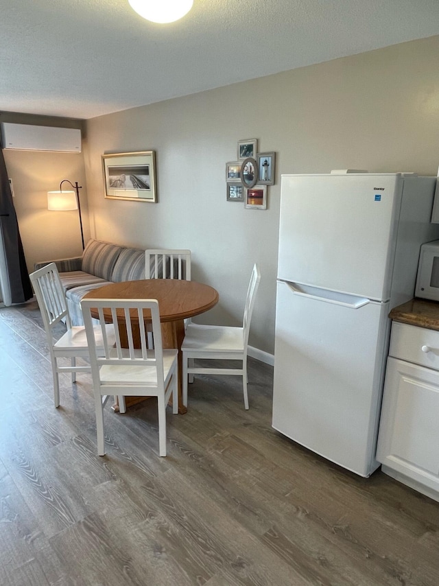 dining room with an AC wall unit, wood-type flooring, and breakfast area