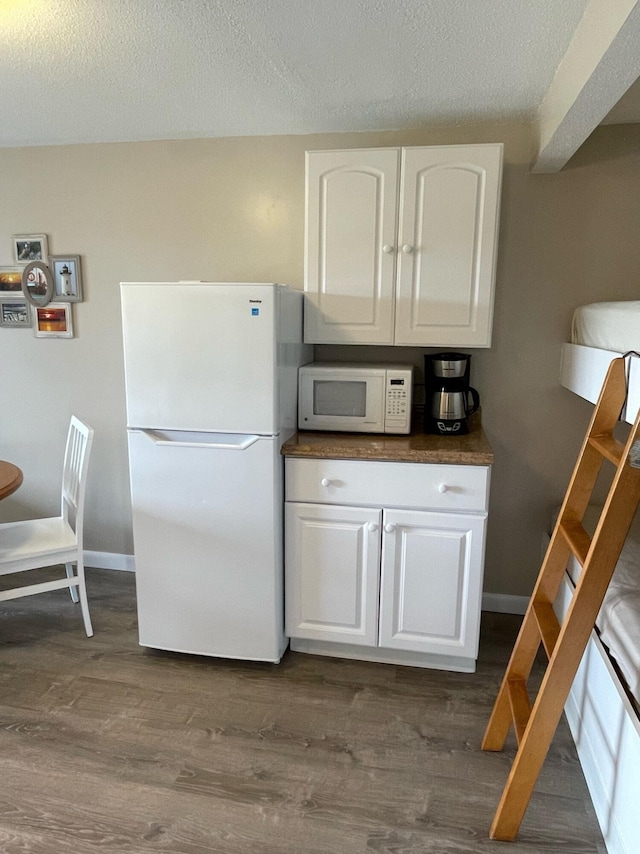 kitchen featuring white cabinets, white appliances, a textured ceiling, and dark hardwood / wood-style flooring