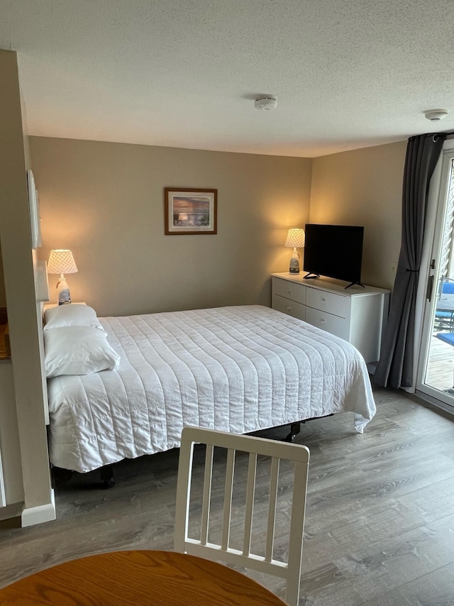 132 Shore Rd Unit 3, Truro, MA 02666 - bedroom featuring wood finished floors, access to exterior, multiple windows, and a textured ceiling