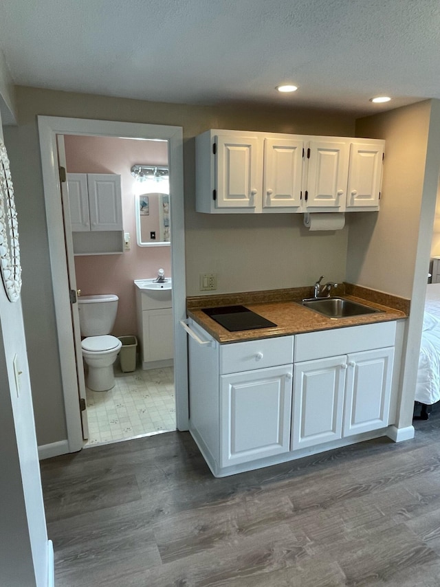 kitchen with sink, white cabinetry, black electric stovetop, and wood-type flooring