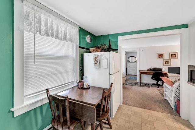 dining space featuring a healthy amount of sunlight, light colored carpet, and a fireplace