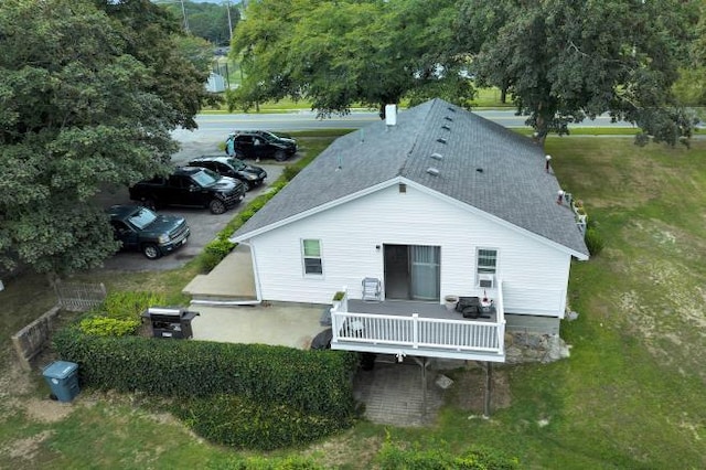 rear view of house featuring a wooden deck and a lawn