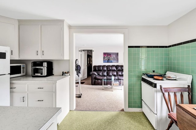 kitchen featuring light colored carpet, white appliances, white cabinetry, and tile walls