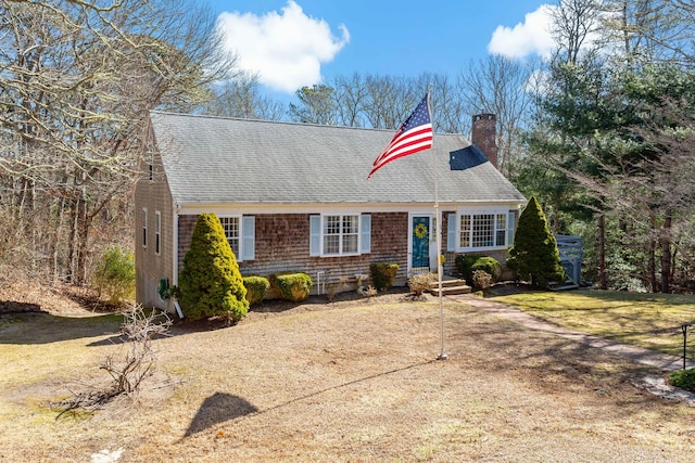 view of front of property with a front lawn, a chimney, and a shingled roof