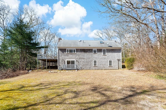 back of property featuring a carport, a lawn, a chimney, and a wooden deck