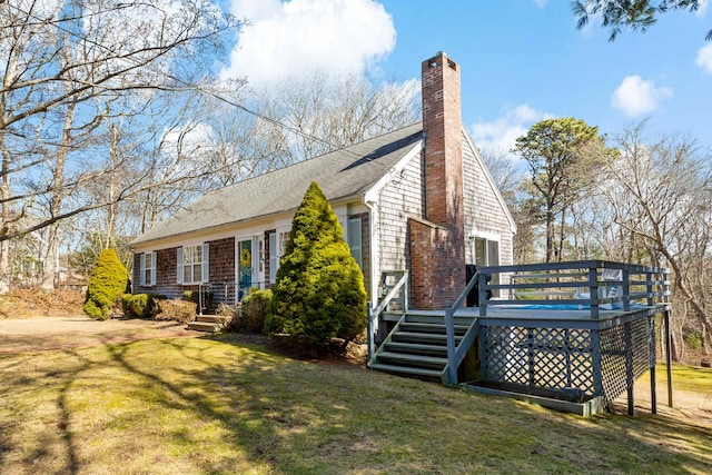 view of front of house with a deck, a chimney, a front yard, and a shingled roof