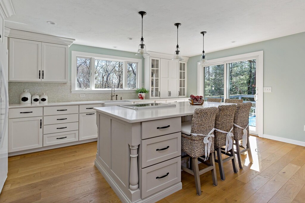 kitchen with a breakfast bar, light wood-style flooring, a sink, light countertops, and backsplash