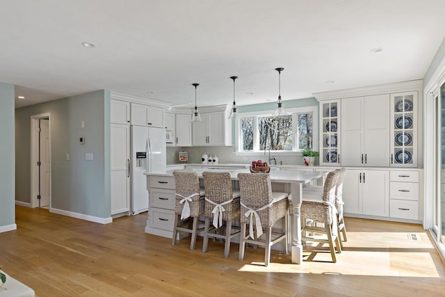 kitchen featuring white cabinetry, light countertops, light wood-style floors, and white fridge with ice dispenser