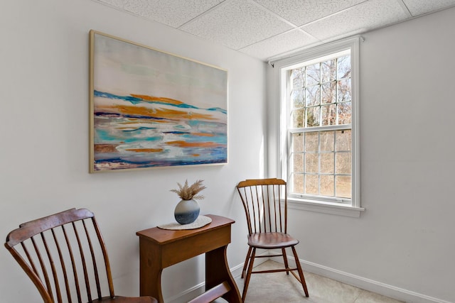 sitting room with a drop ceiling and baseboards