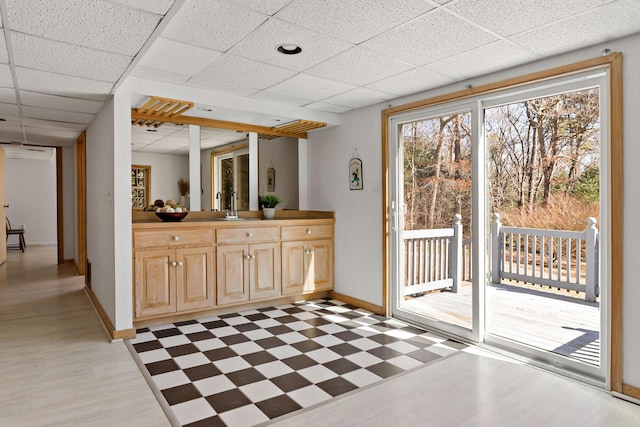 interior space with a sink, a paneled ceiling, baseboards, and light floors