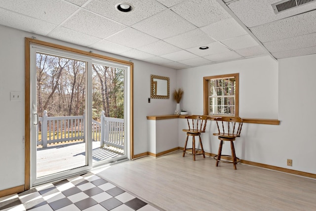 doorway to outside featuring a drop ceiling, visible vents, and baseboards