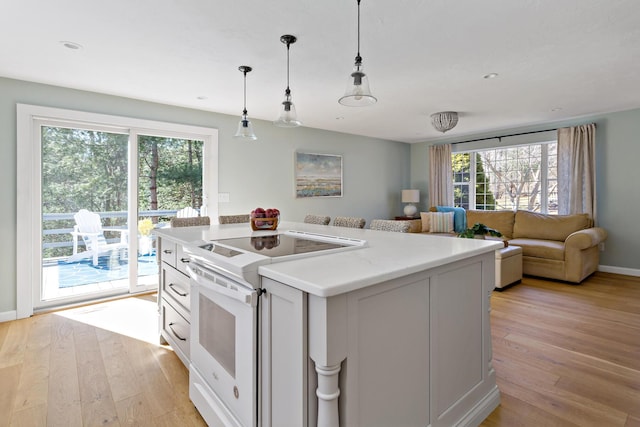 kitchen featuring light countertops, decorative light fixtures, white electric range, and light wood-style floors