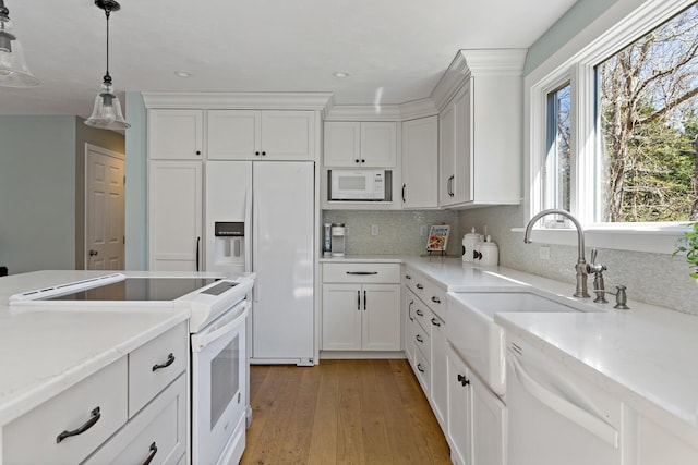 kitchen featuring a sink, white appliances, light wood-style floors, and white cabinets