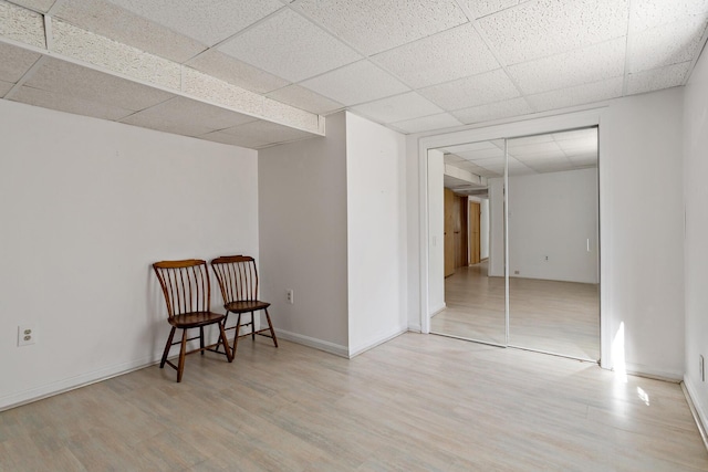 living area with wood finished floors, baseboards, and a drop ceiling