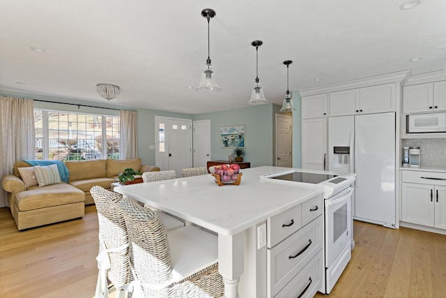 kitchen featuring white appliances, white cabinets, light wood-style floors, and a center island with sink