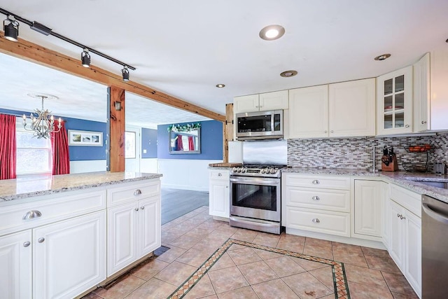 kitchen featuring light tile patterned floors, stainless steel appliances, decorative backsplash, glass insert cabinets, and white cabinets