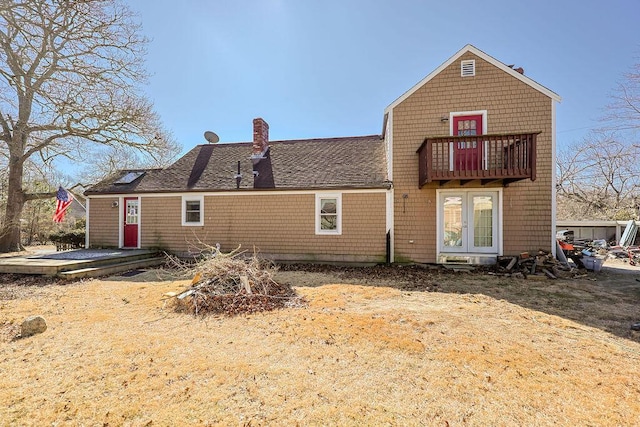 rear view of house featuring a balcony, a shingled roof, a chimney, and french doors