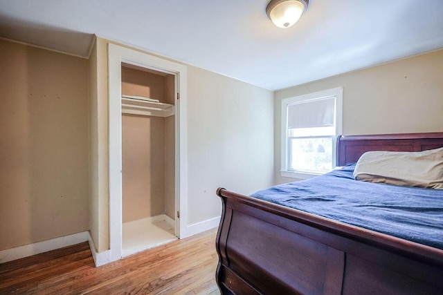 bedroom with a closet, light wood-style flooring, and baseboards