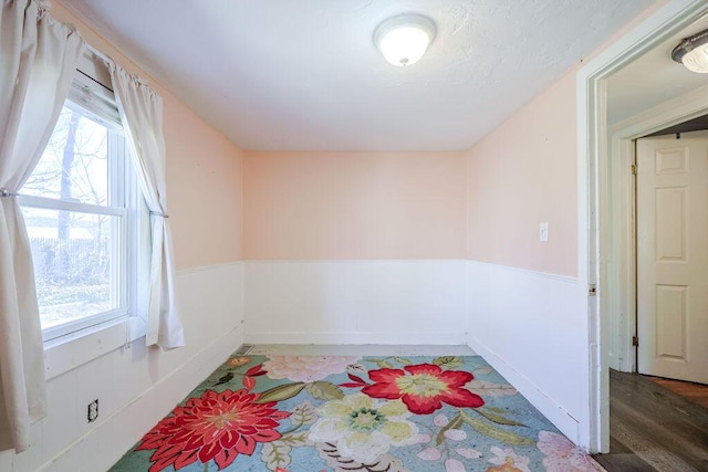 unfurnished room with a healthy amount of sunlight and a wainscoted wall