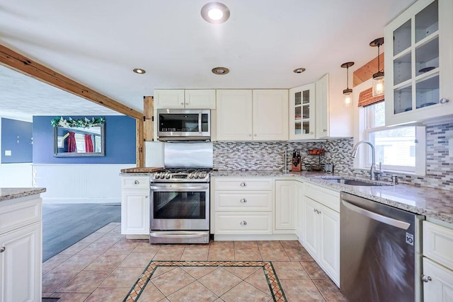 kitchen with light tile patterned floors, tasteful backsplash, appliances with stainless steel finishes, glass insert cabinets, and a sink