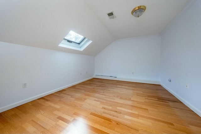 additional living space featuring visible vents, vaulted ceiling with skylight, light wood-style flooring, and baseboards