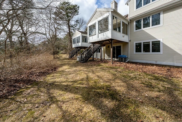 rear view of house featuring a chimney, a sunroom, stairway, and central AC unit