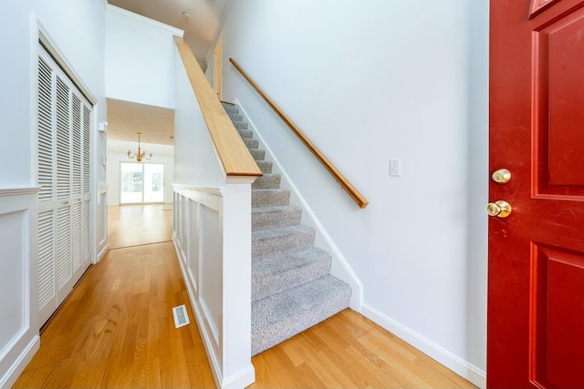 foyer with a notable chandelier, visible vents, light wood-type flooring, baseboards, and stairs