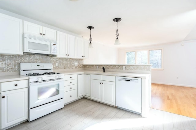 kitchen featuring white appliances, white cabinets, a peninsula, and decorative backsplash