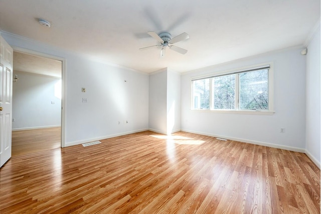 unfurnished room with ceiling fan, light wood-style flooring, visible vents, baseboards, and ornamental molding