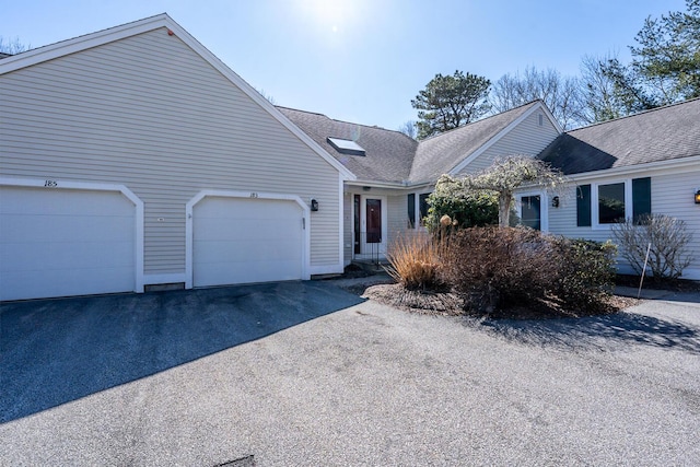 ranch-style home with driveway and roof with shingles