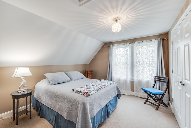 bedroom with lofted ceiling, baseboards, a closet, and light colored carpet