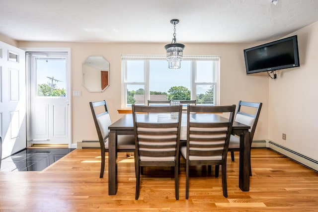 dining room with a chandelier, a baseboard heating unit, and wood-type flooring