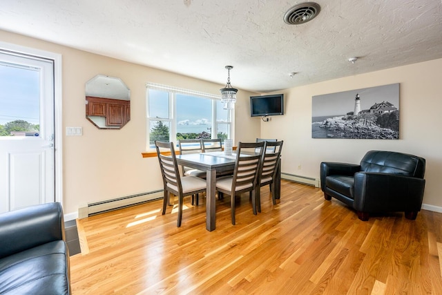 dining area with light hardwood / wood-style flooring, a textured ceiling, and a baseboard heating unit